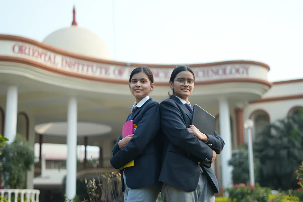 Two students in front of the Oriental Institute of Science & Technology building