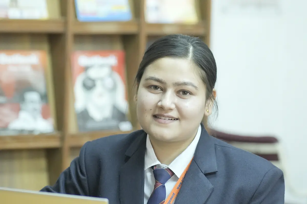 A student with a laptop in front of a magazine rack