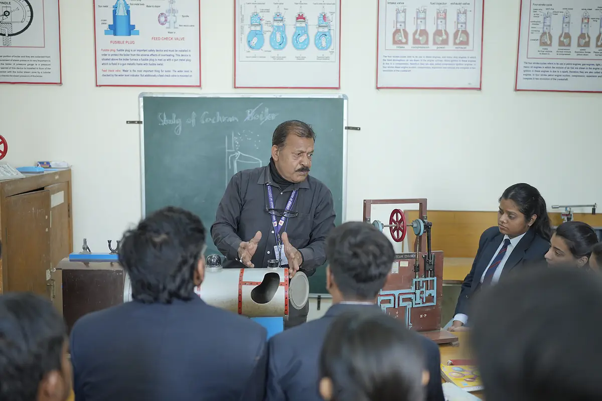 A faculty member explains a working model to students in the lab