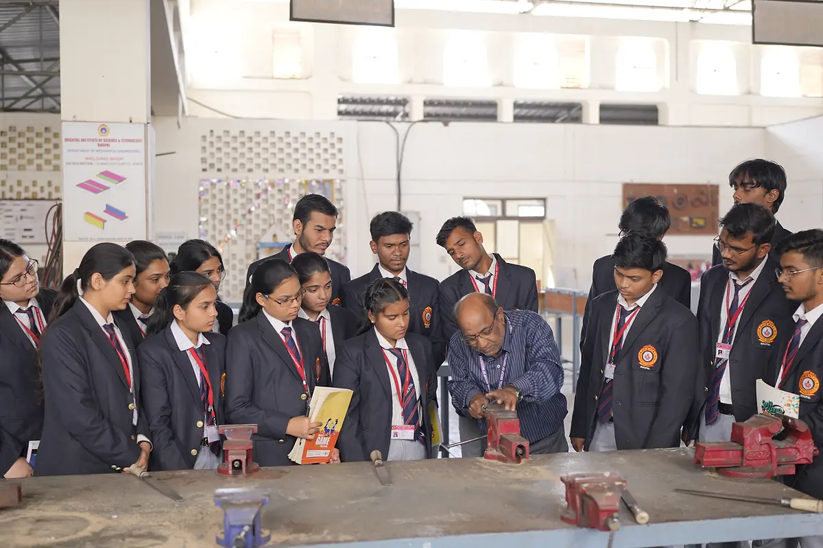 Students gather around a bench vice in the workshop