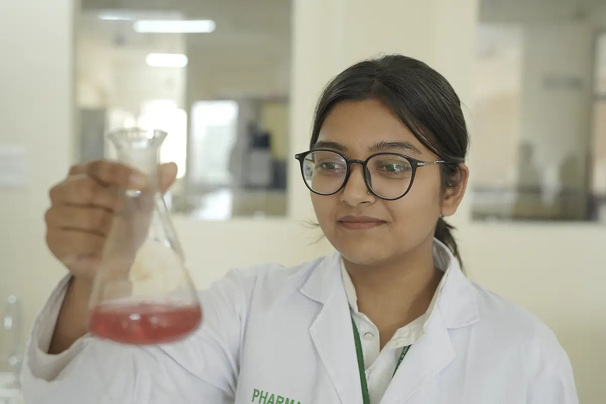 A pharmacy student holds a conical flask in the lab